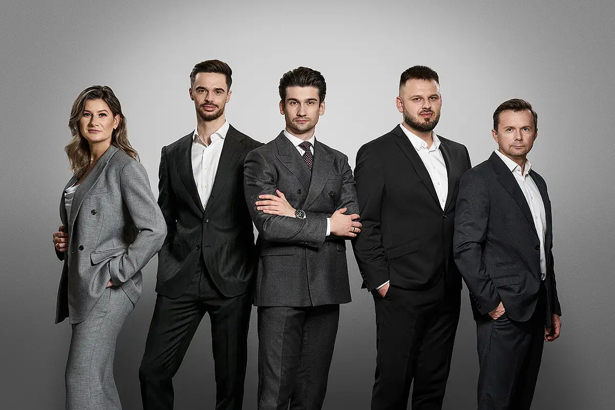 Grupowe zdjęcie zespołu pracowników w ciemnych garniturach